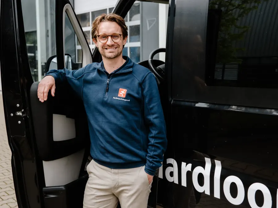 Operator van Hardloopuitslagen.nl kijkt in de lens bij de bus