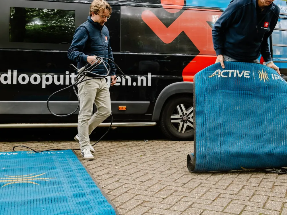Tijdwaarnemingsmat wordt uitgerold naast de Hardloopuitslagen.nl bus